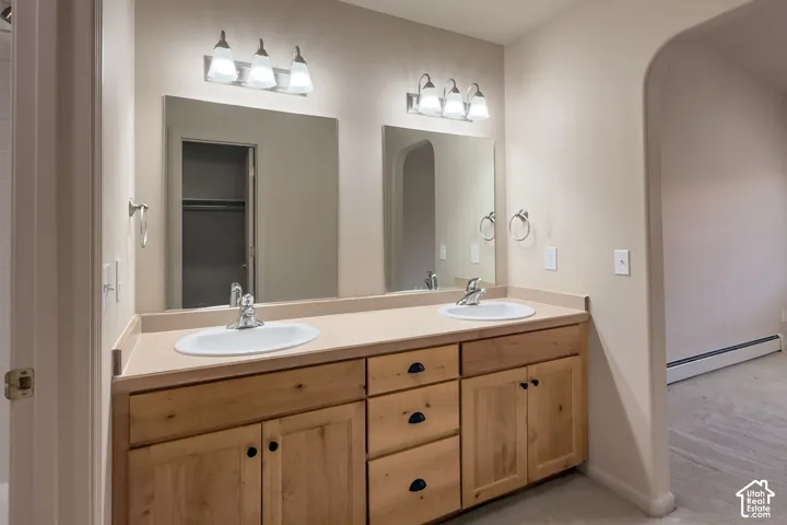 Dual vanity with light wood cabinetry, white oval sinks, and a light-toned countertop