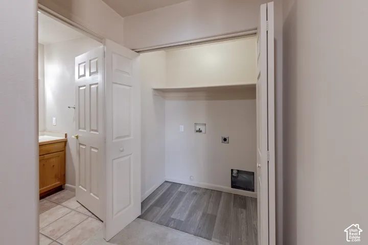 Dedicated laundry alcove with wood-finish flooring and integrated shelving