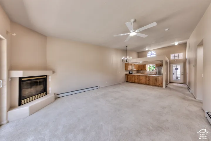 Spacious living area featuring a fireplace with a light-colored surround, vaulted ceilings, and light-toned carpet flooring