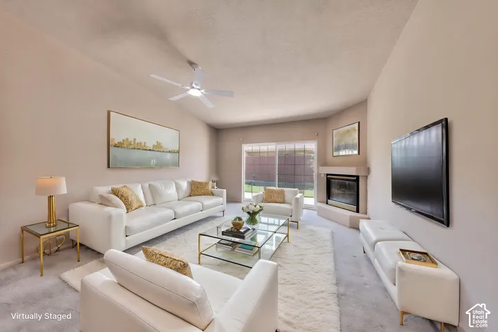 Living room featuring a vaulted ceiling with a ceiling fan, a fireplace with a mantel, and sliding glass doors