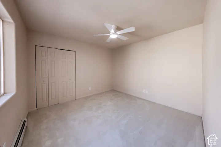 Carpeted room featuring a ceiling fan with integrated lighting, a window, baseboard heating, and a bi-fold closet with panel doors