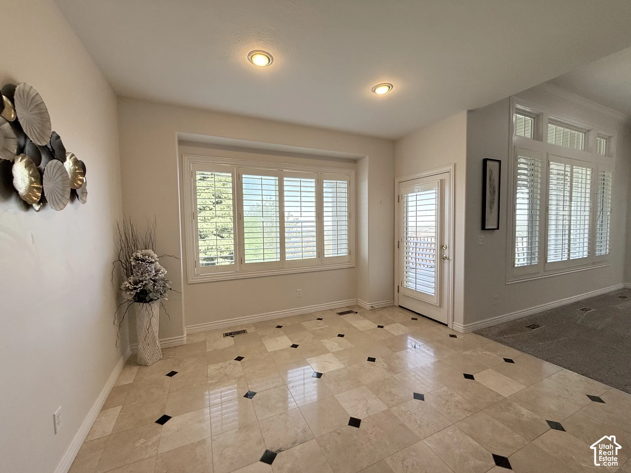 Tiled entryway featuring a decorative inlay pattern, recessed lighting, and white plantation shutters on the window and glass-paned door