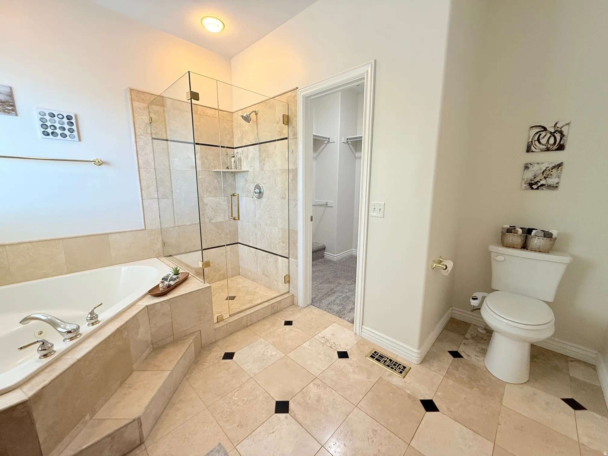 Spacious bathroom featuring a glass-enclosed walk-in shower with tile surround, a built-in soaking tub with tiled steps, and patterned tile flooring