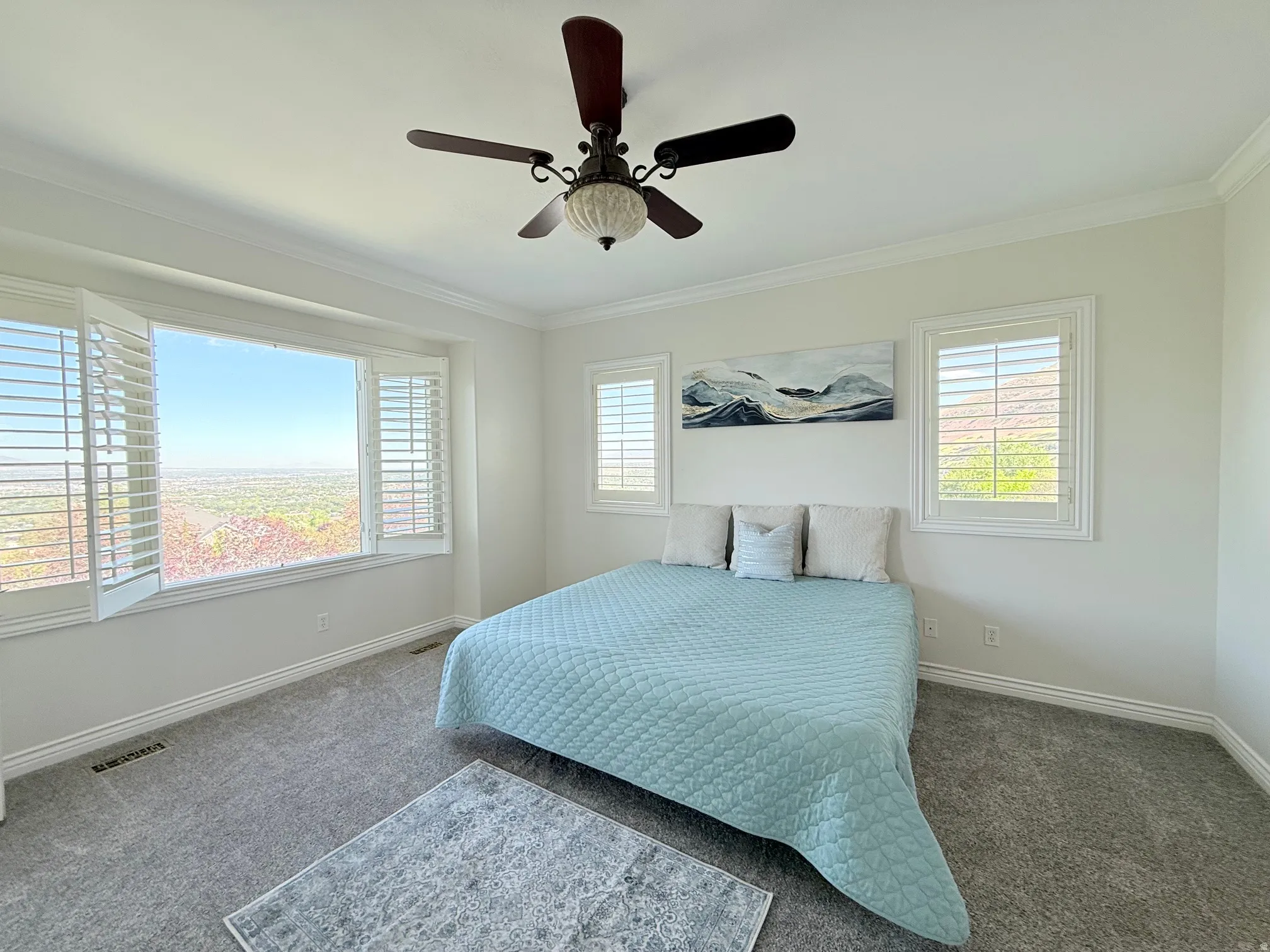 Spacious room featuring a wide picture window, two additional windows, and white plantation shutters