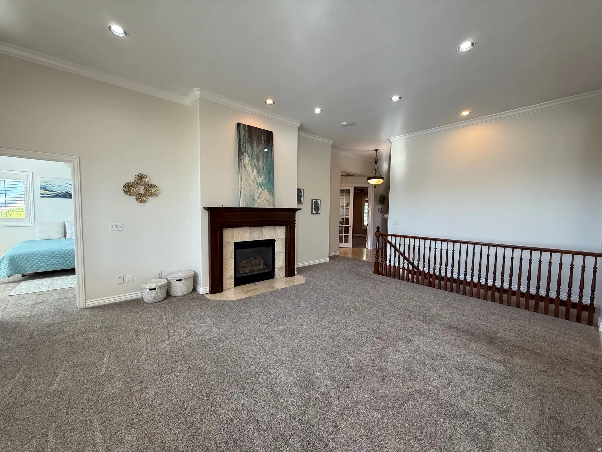 Living area featuring a dark wood mantel fireplace with a light tile surround, crown molding, recessed lighting, and grey carpet flooring