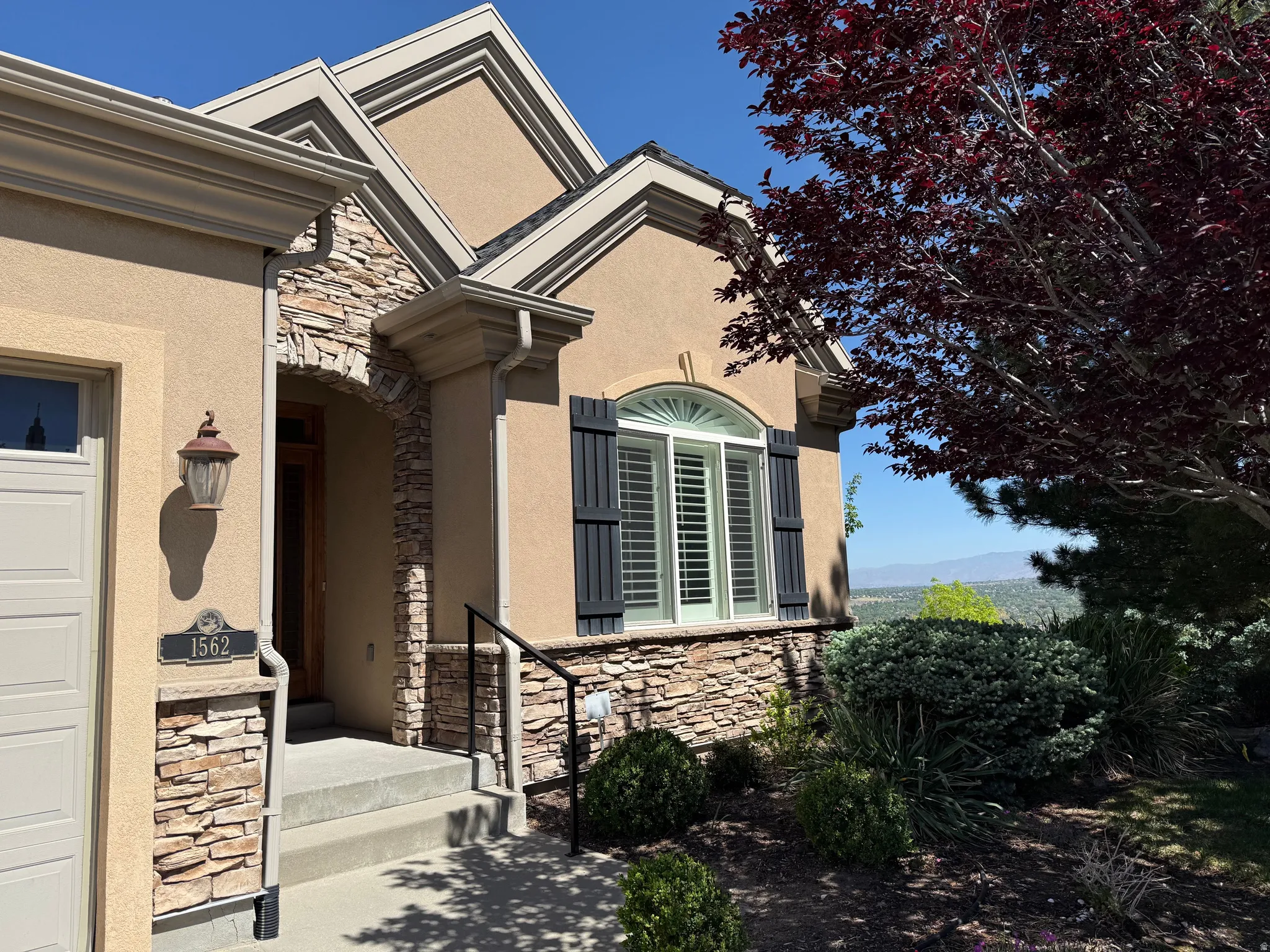 Stucco exterior with stone accents, featuring an arched entryway with a wooden door and a decorative sconce