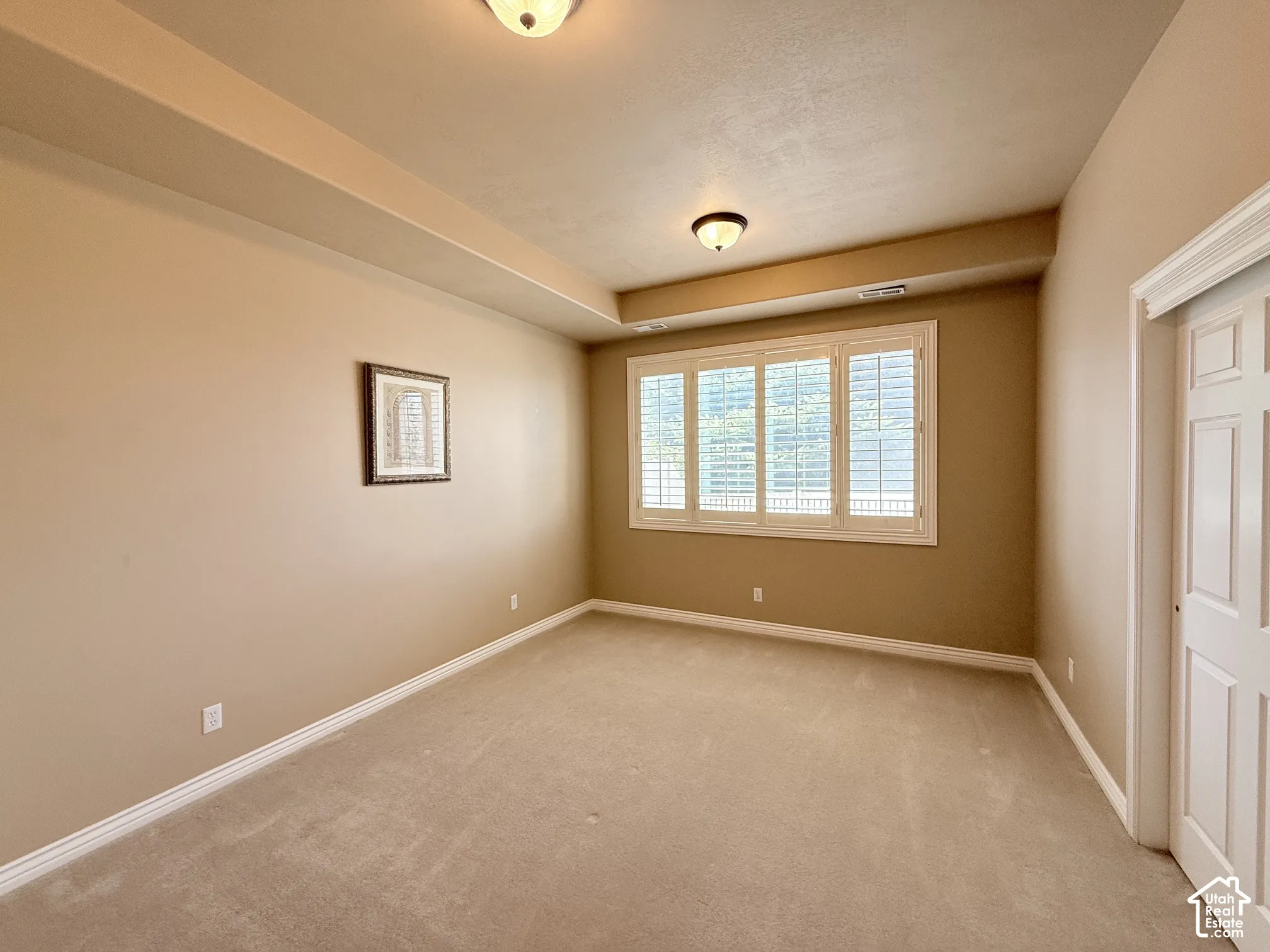 Tray ceiling with recessed lighting, integrated window blinds, and paneled interior door