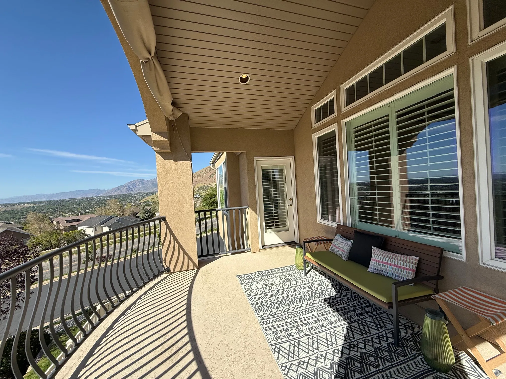 Covered balcony featuring a curved wrought iron railing, stucco exterior, and a mountain backdrop