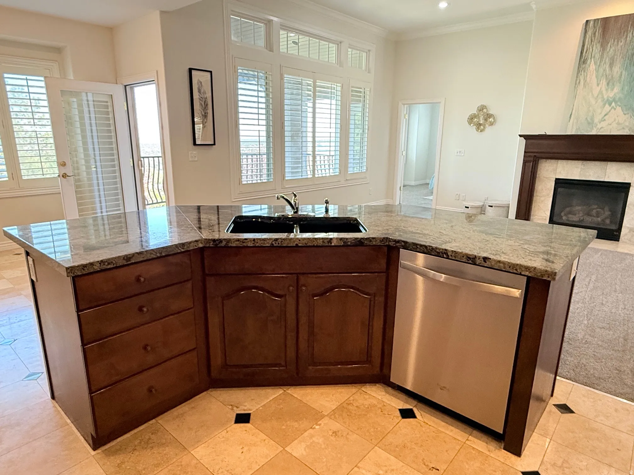 Angled kitchen island featuring granite countertops, an integrated double basin sink, and stainless steel dishwasher