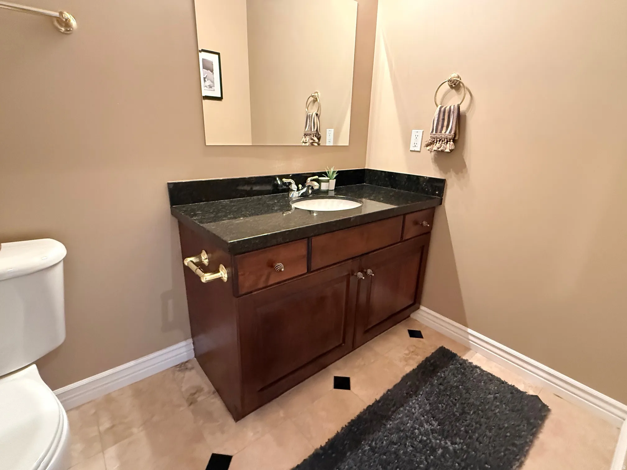 Wood-finish vanity with a dark countertop and integrated sink