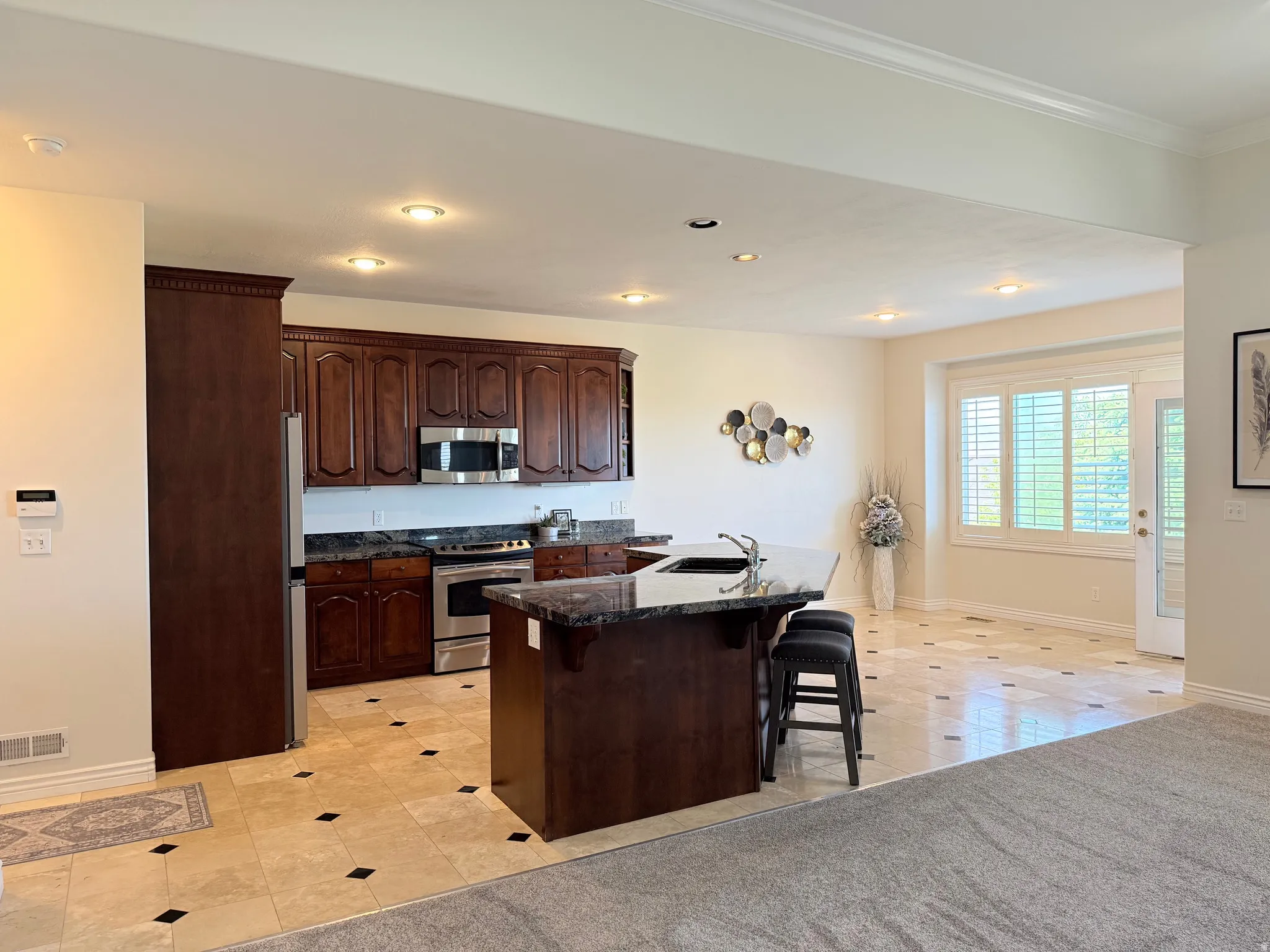 Kitchen featuring dark wood cabinetry, stainless steel appliances, and dark granite countertops