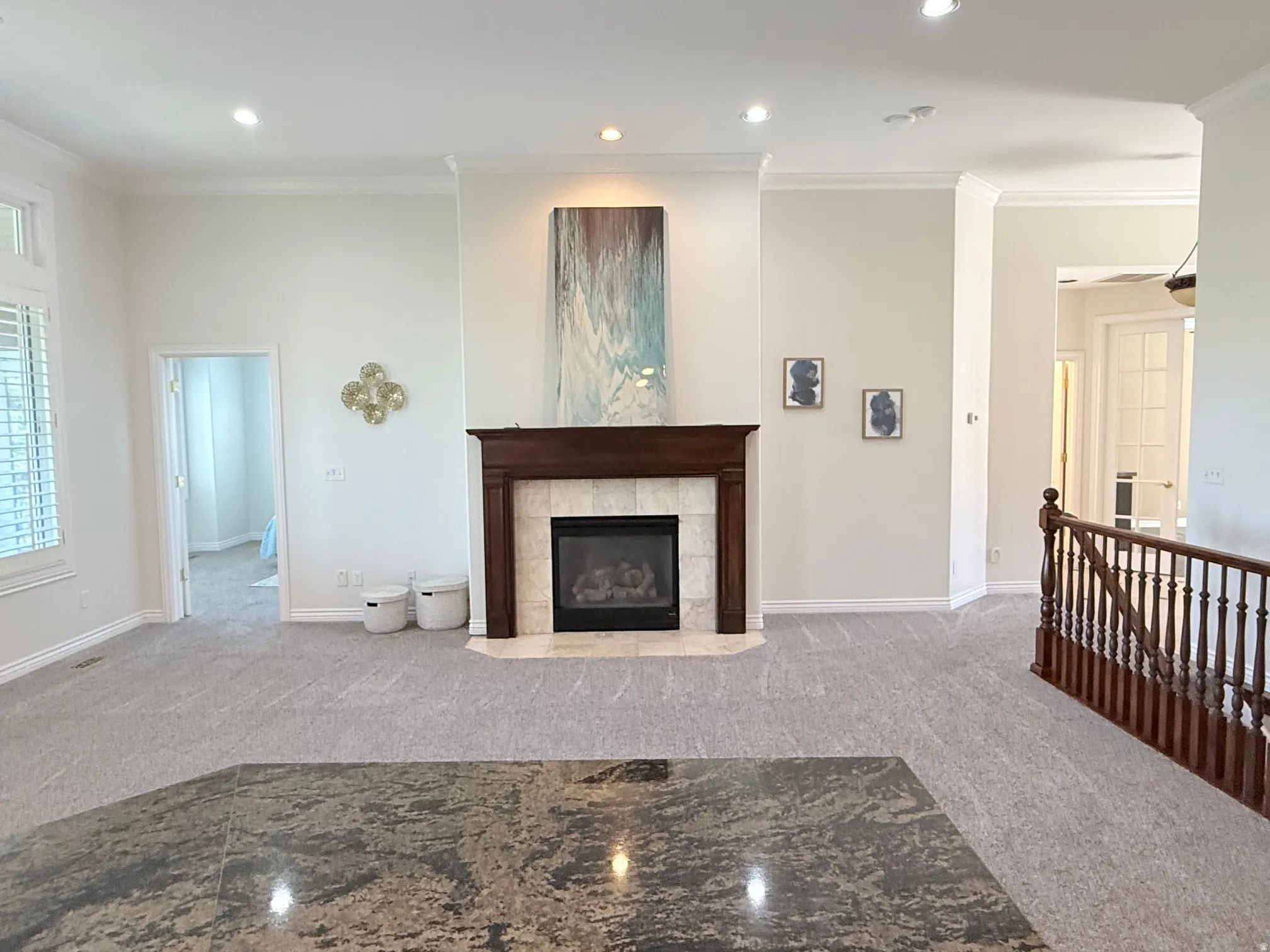 Living area featuring a traditional fireplace with wood mantel and tile surround, recessed lighting, crown molding, and light gray patterned carpet
