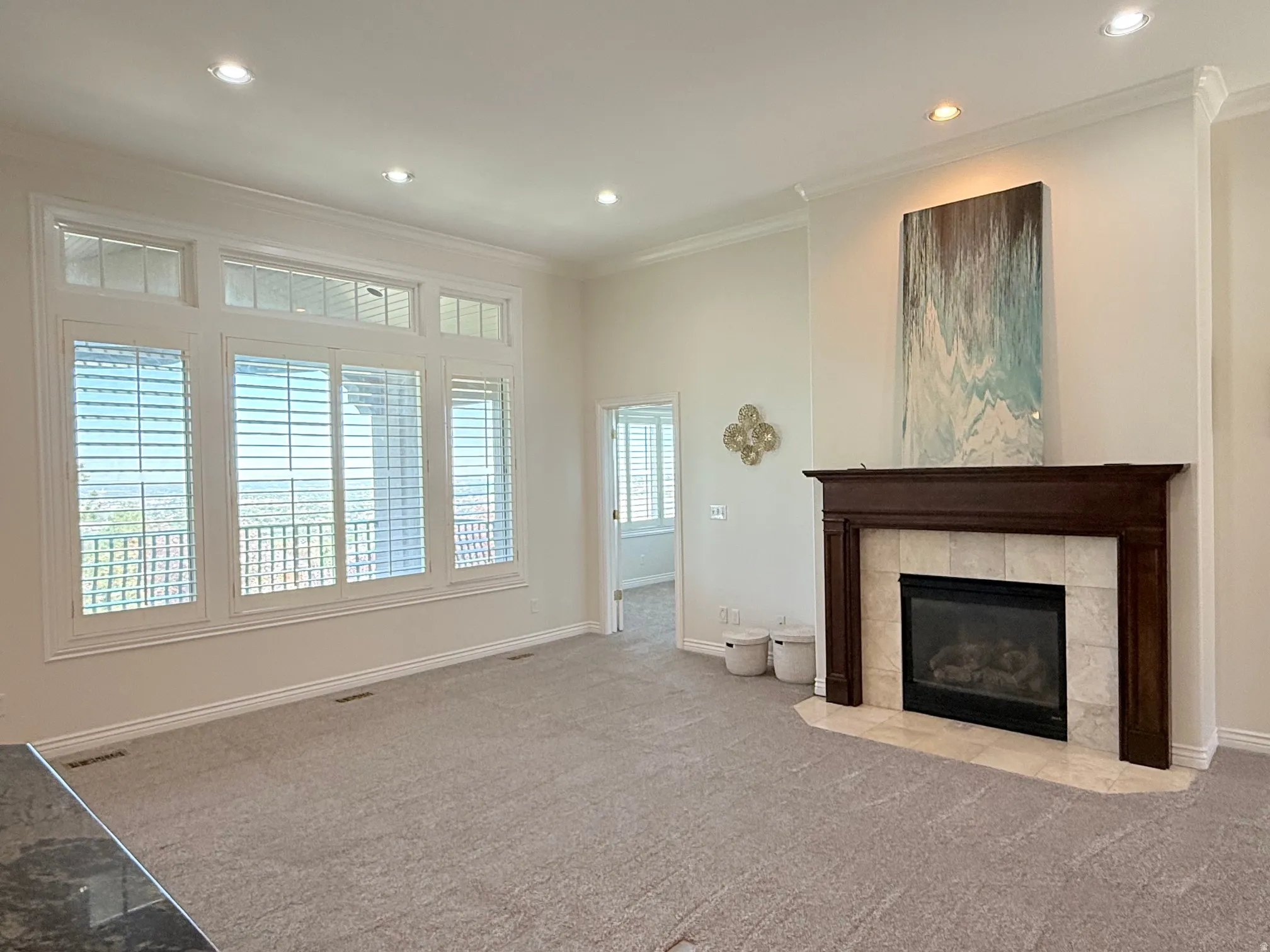 Spacious living area featuring a central fireplace with a dark wood mantel and light-toned tile surround