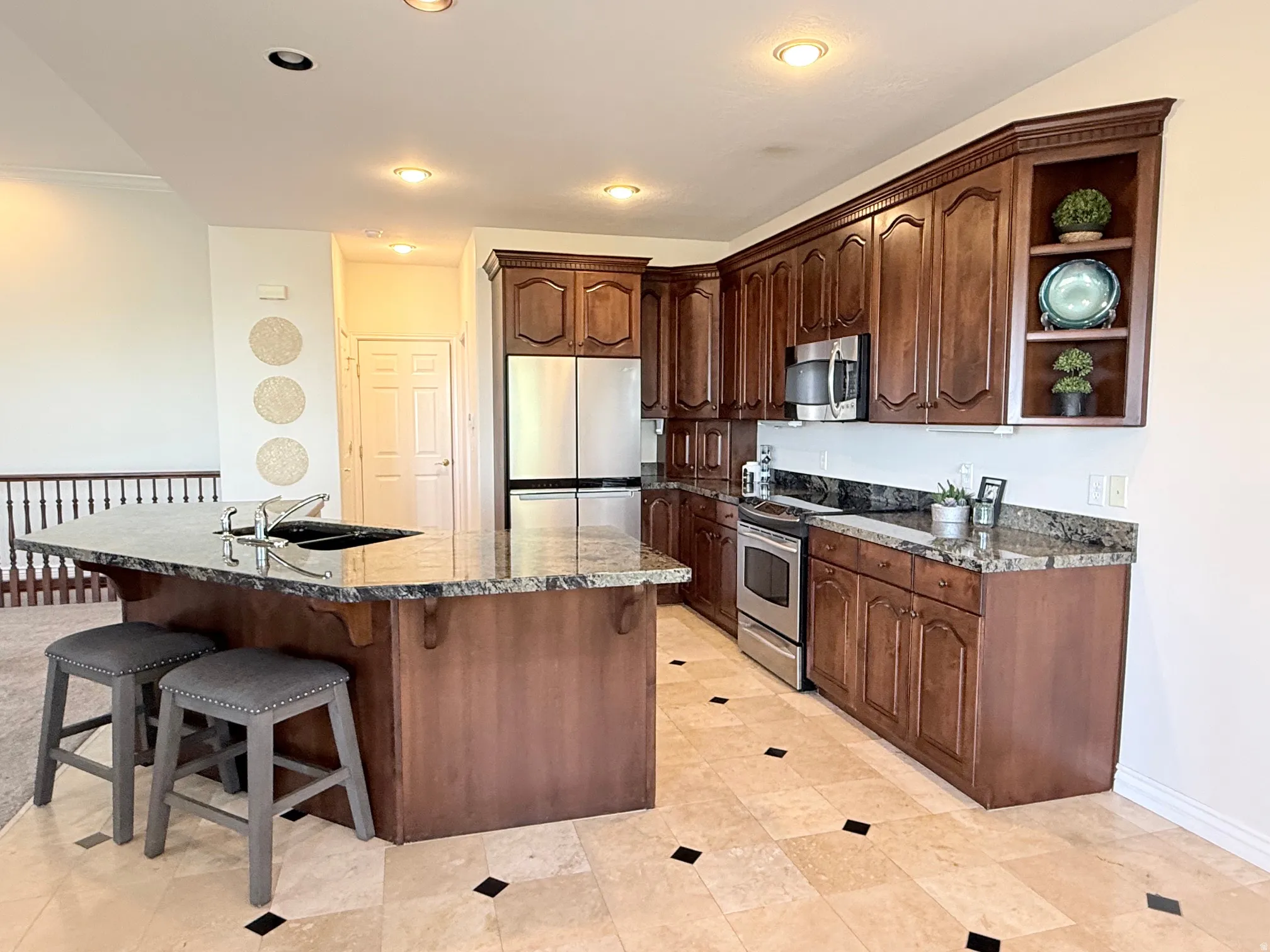 Kitchen featuring a central island with an integrated sink, granite countertops, and rich wood-finish cabinetry