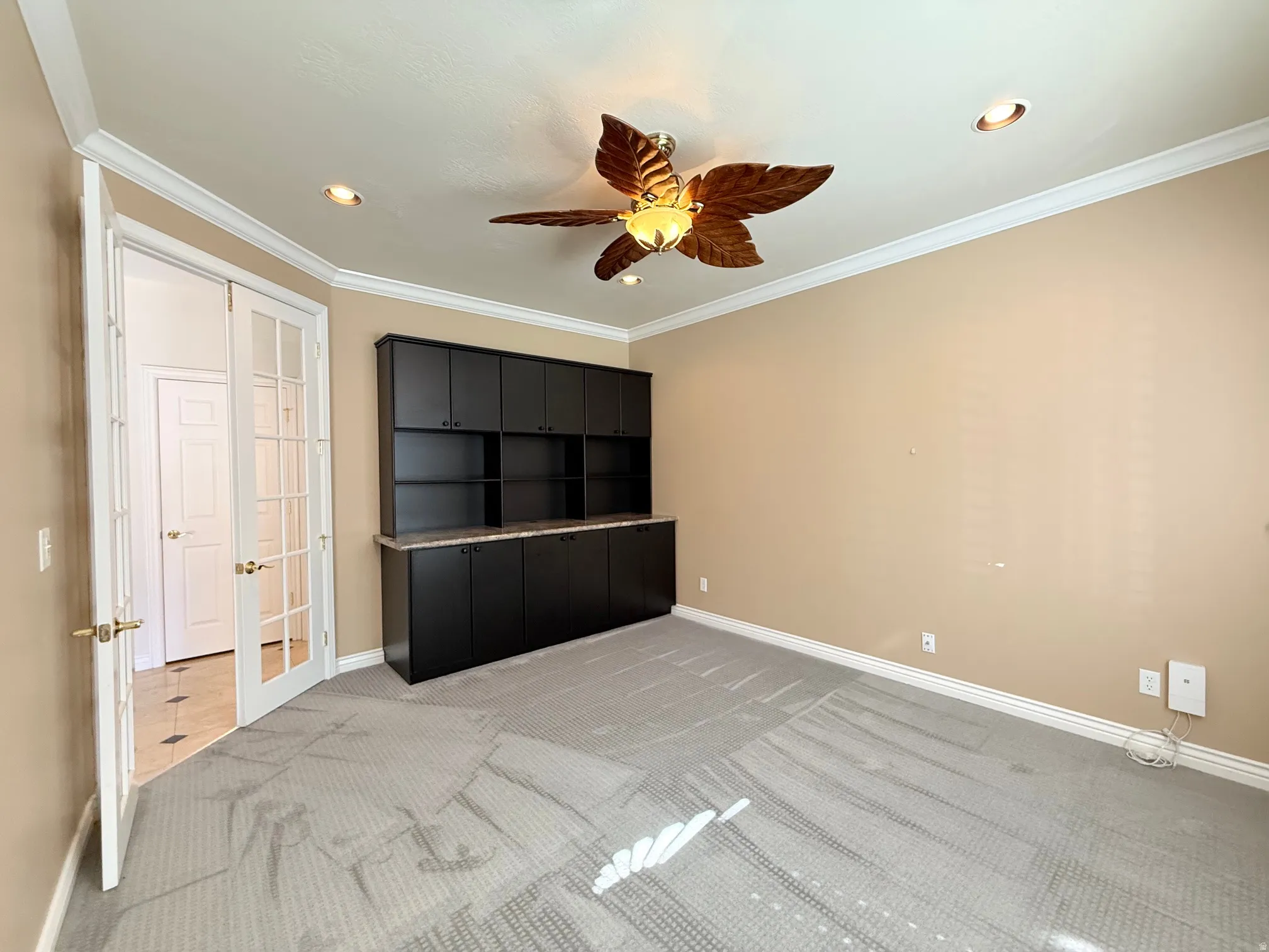 Room featuring built-in dark cabinetry with a light-toned countertop, recessed lighting, and a ceiling fan with decorative blades