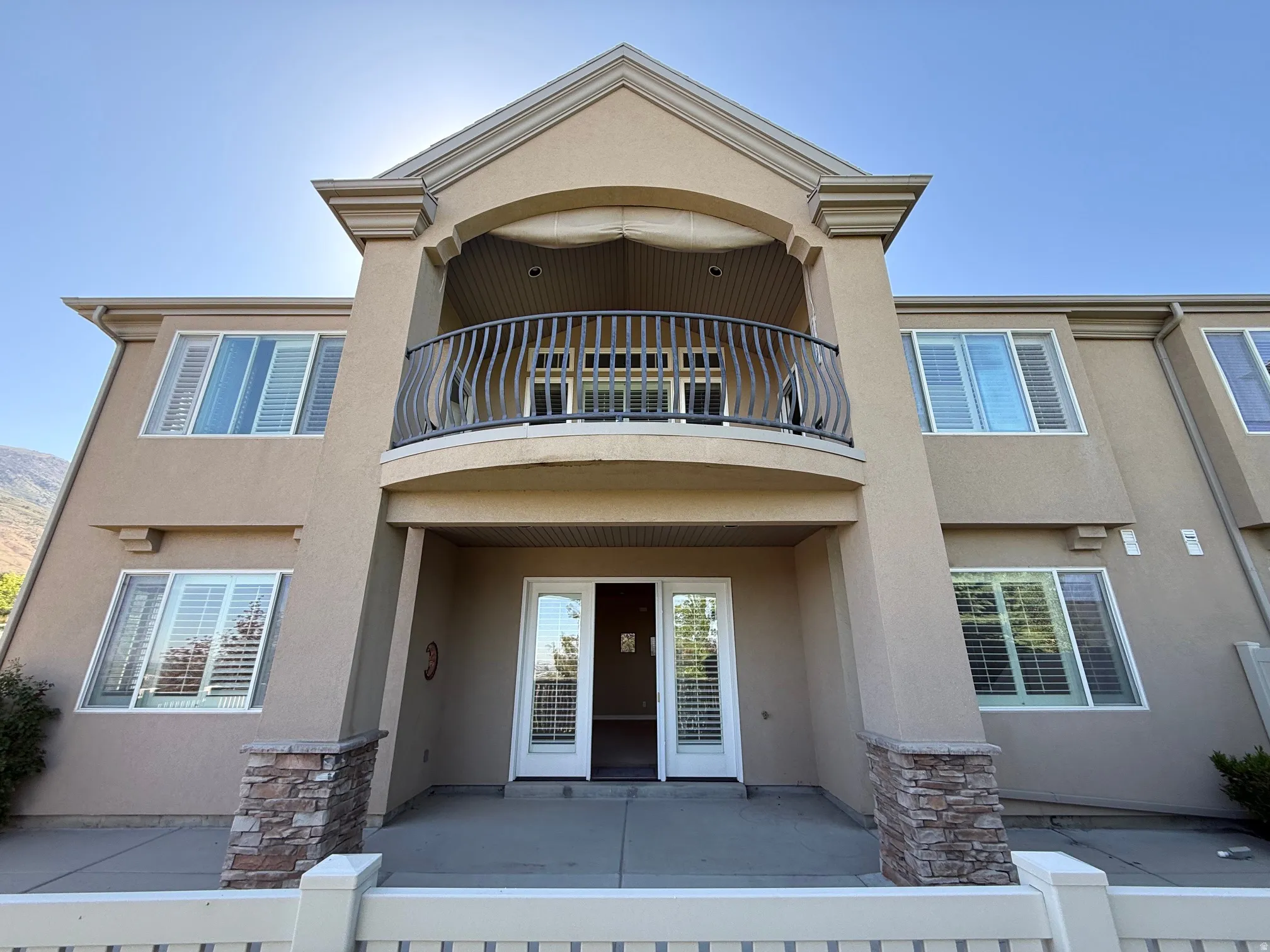 Stucco exterior featuring a second-story balcony with decorative iron railings