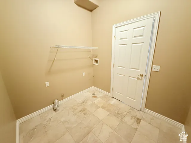 Utility area featuring large-format tile flooring, a six-panel door, and a wall-mounted wire storage shelf