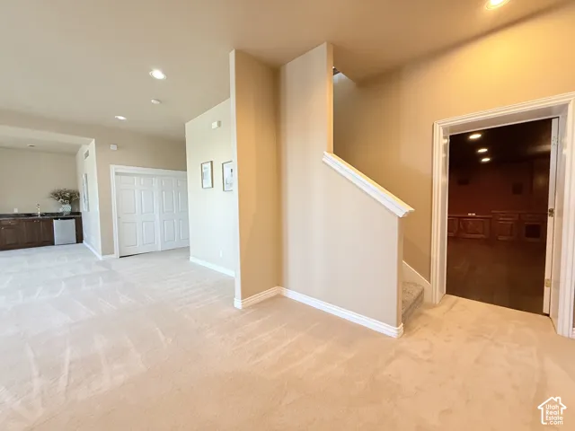 Expansive carpeted area featuring a wet bar with dark wood cabinetry and a stainless steel under-counter refrigerator