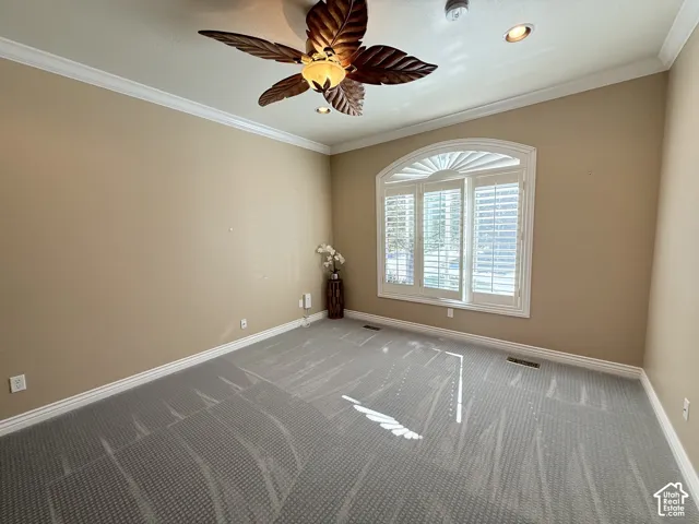 Room featuring an arched window with plantation shutters, crown molding, and a decorative ceiling fan