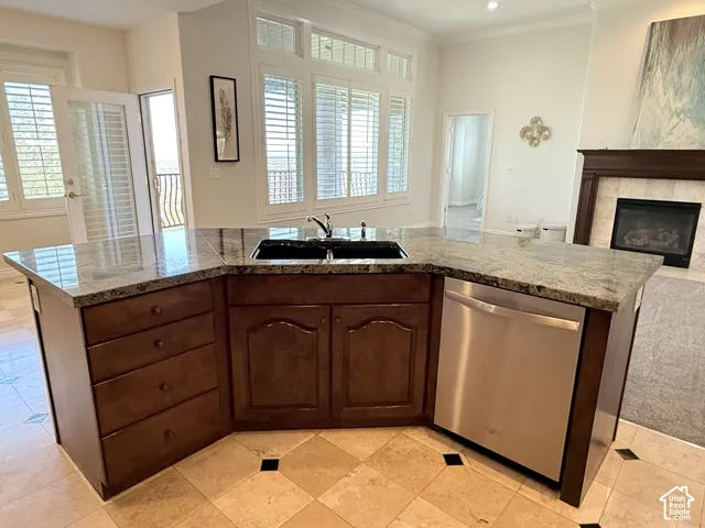 Angled kitchen island featuring granite countertops, an integrated double basin sink, and stainless steel dishwasher