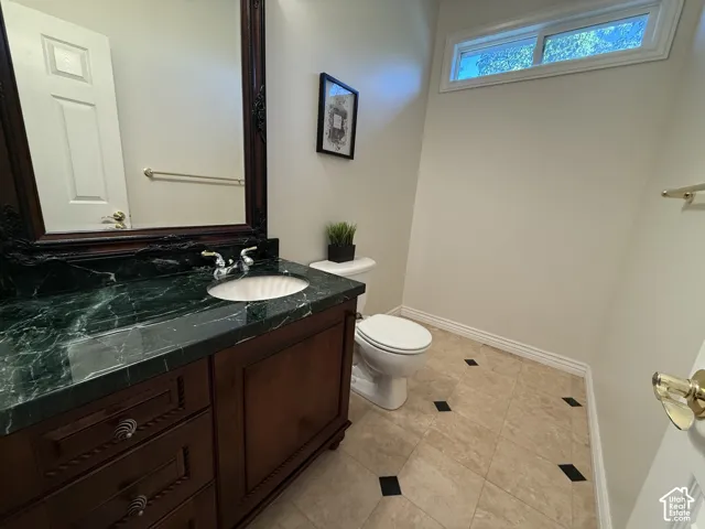 Bathroom vanity featuring a dark wood cabinet with decorative drawer pulls, a green marbled countertop, and an undermount sink with chrome fixtures