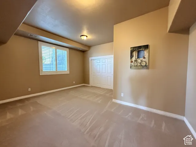 Room featuring neutral-toned walls, white baseboards, and wall-to-wall carpeting