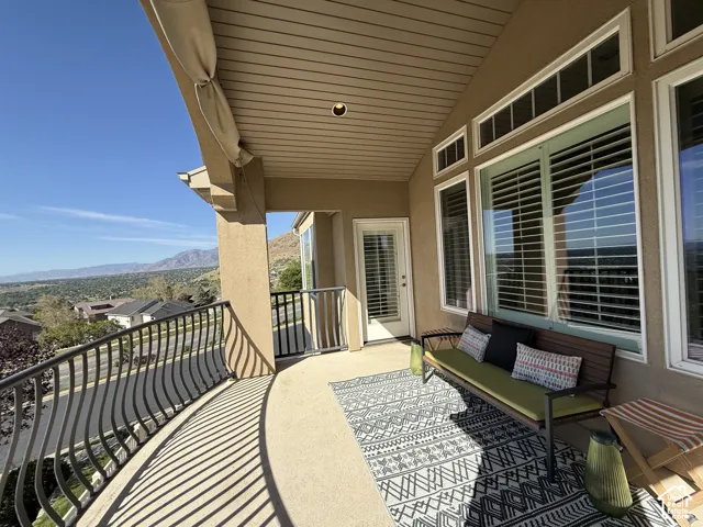 Covered balcony featuring a curved wrought iron railing, stucco exterior, and a mountain backdrop