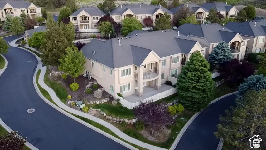 Stucco exterior residence with a dark gray shingle roof, featuring multiple balconies and mature landscaping