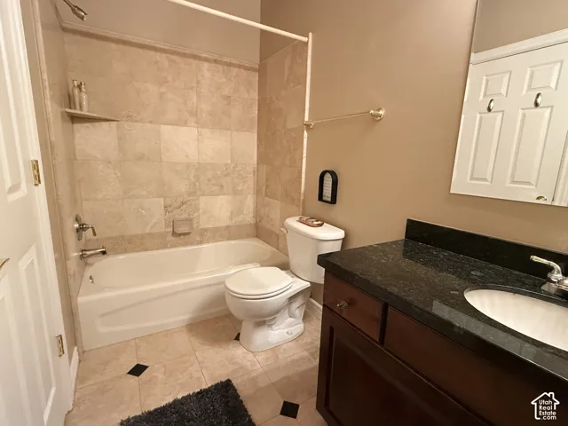 Bathroom featuring a tiled shower surround, integrated bathtub, and a dark wood vanity with a stone countertop and undermount sink
