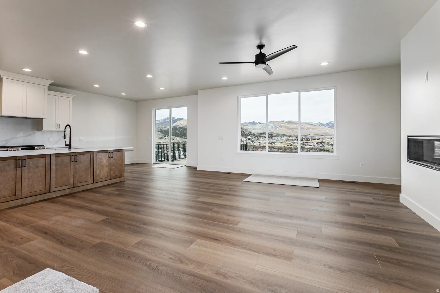 Open-concept living area featuring wood-finish flooring, a contemporary ceiling fan, and recessed lighting