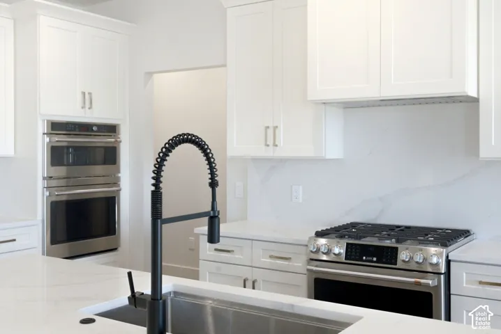 White cabinetry with brushed gold handles and cafe appliances.