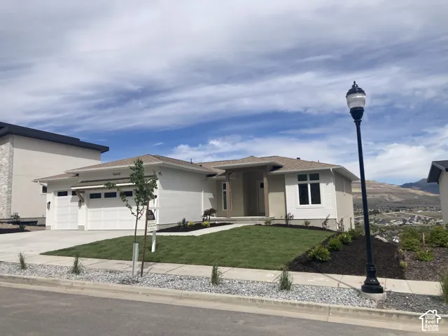 Contemporary exterior with a multi-car garage, manicured lawn, and paved driveway