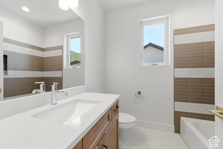Bathroom featuring a white rectangular undermount sink, a chrome single-handle faucet, a wood-finish vanity with bronze hardware, a large wall-mounted mirror, and white hexagonal floor tiling