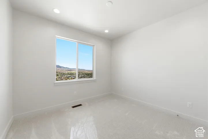 Bright room featuring a large double-pane window, recessed lighting, neutral carpeting, and white baseboards