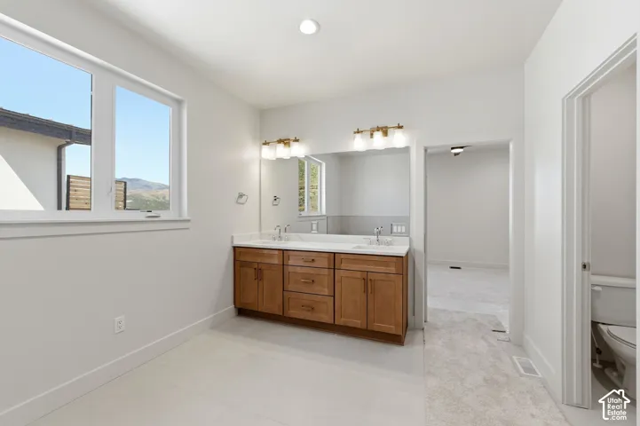 Bathroom featuring a double vanity with wood-finish cabinetry, white countertops, and dual mirrors