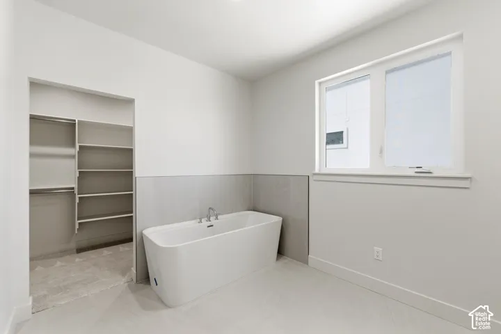 Freestanding soaking tub with chrome fixtures, set against a tiled half-wall