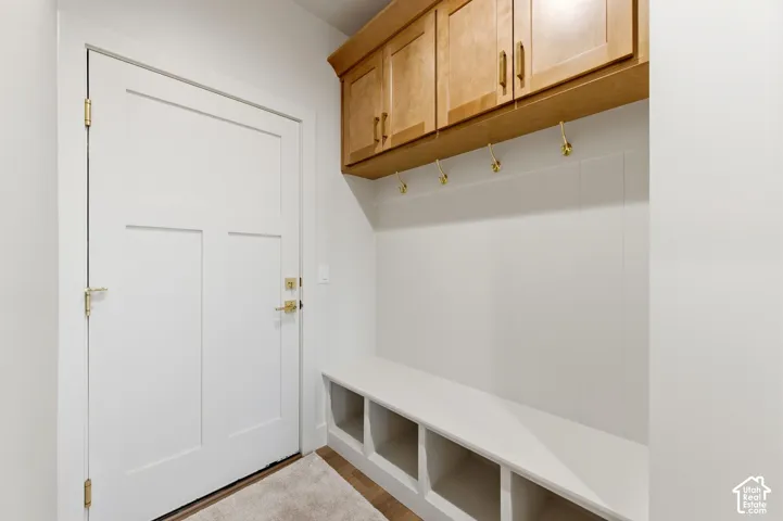 Entryway mudroom with white paneled wainscoting, a built-in bench featuring cubby storage, and overhead wood-finish cabinetry