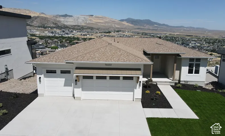 Contemporary ranch-style residence featuring a two-car garage, a covered entry porch, and a concrete driveway