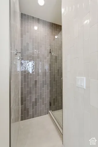 Walk-in shower featuring gray subway tile, glass enclosure, and light-toned tile flooring