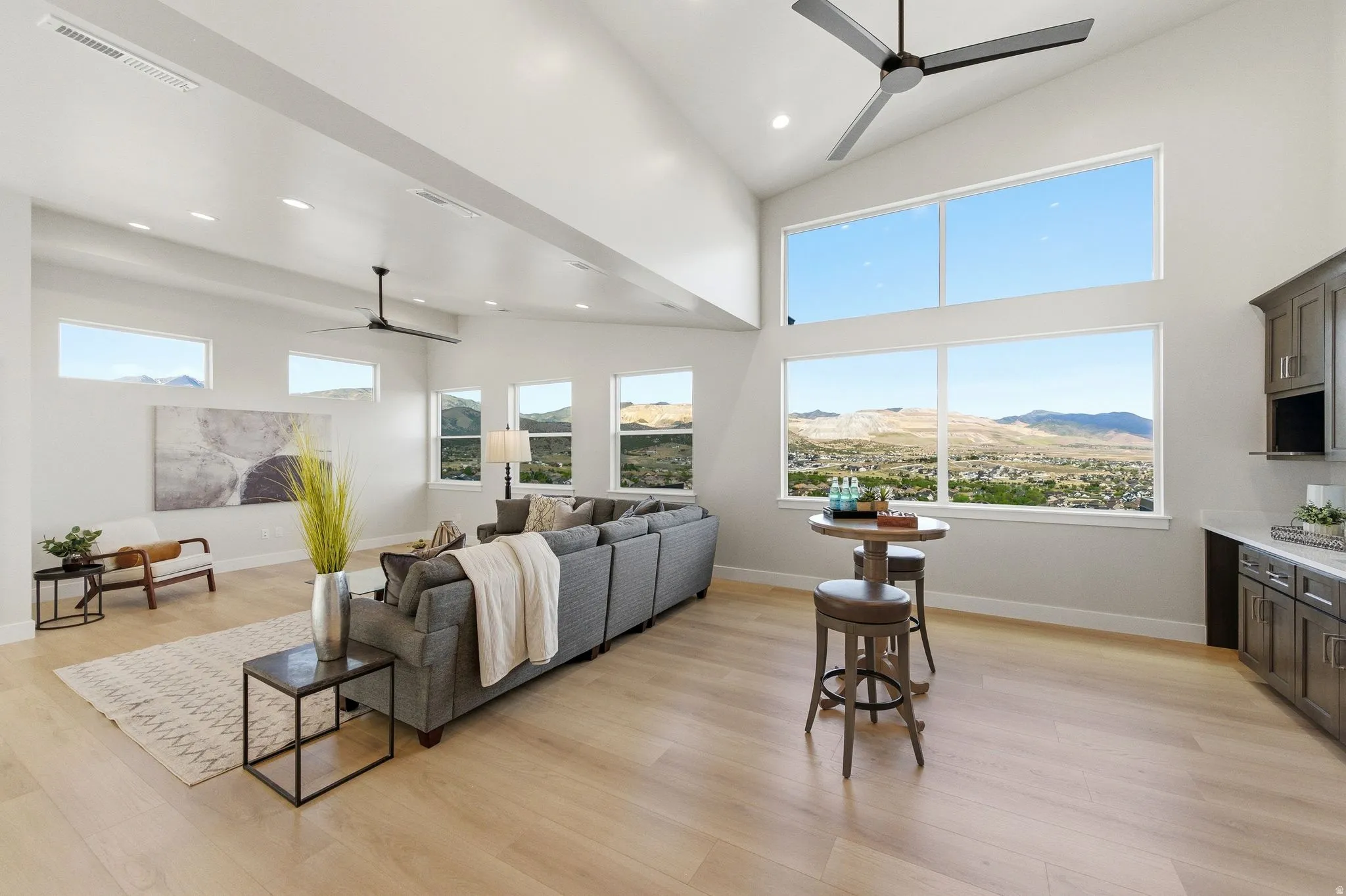 Vaulted great room with light wood-finish flooring, recessed lighting, and multiple large windows