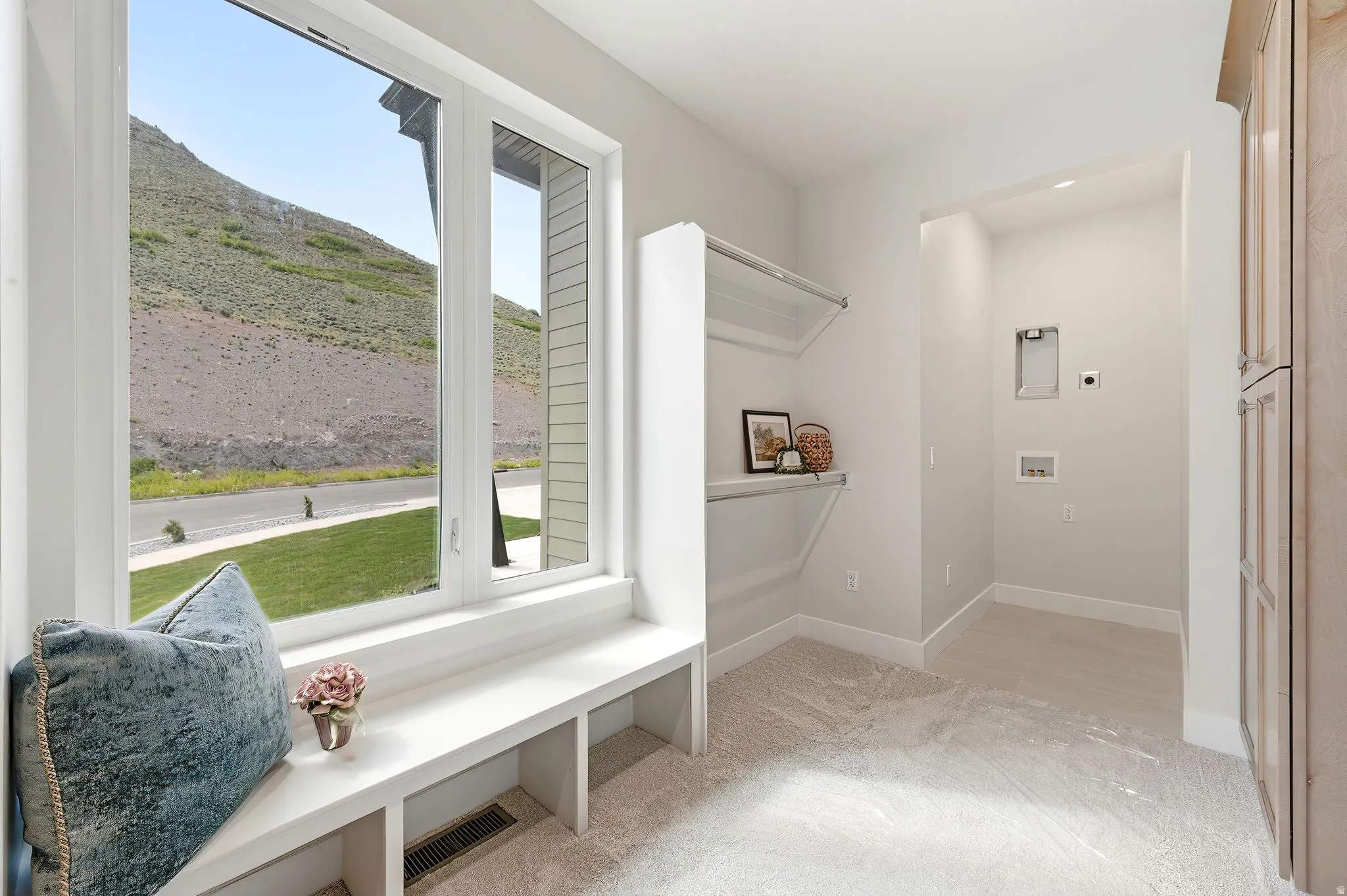 Bright room featuring a large multi-pane window, a built-in window seat with integrated shelving, and light-toned carpeting