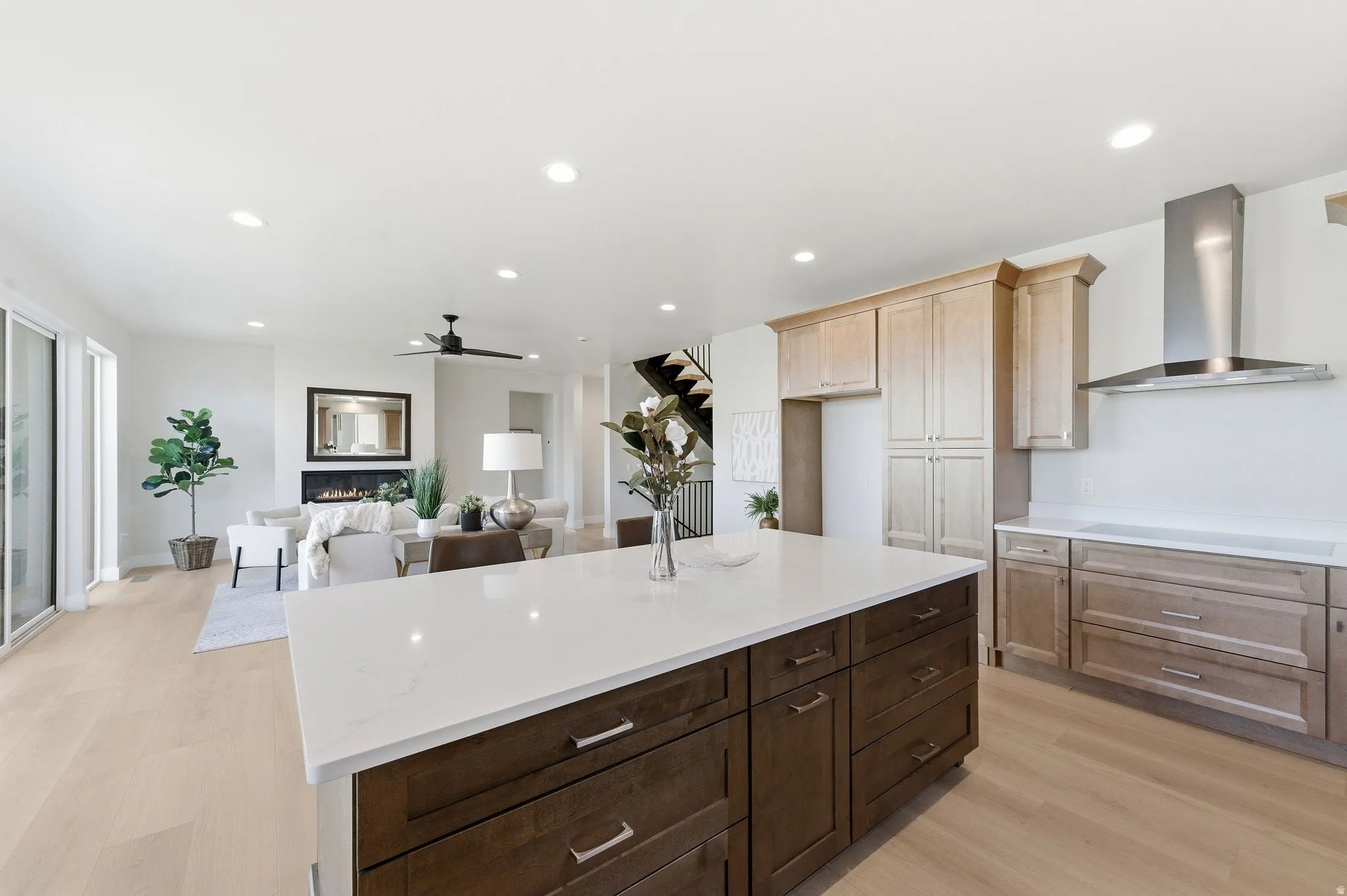 Open-concept living space featuring a central kitchen island with a white countertop, wood-finish flooring, and recessed lighting