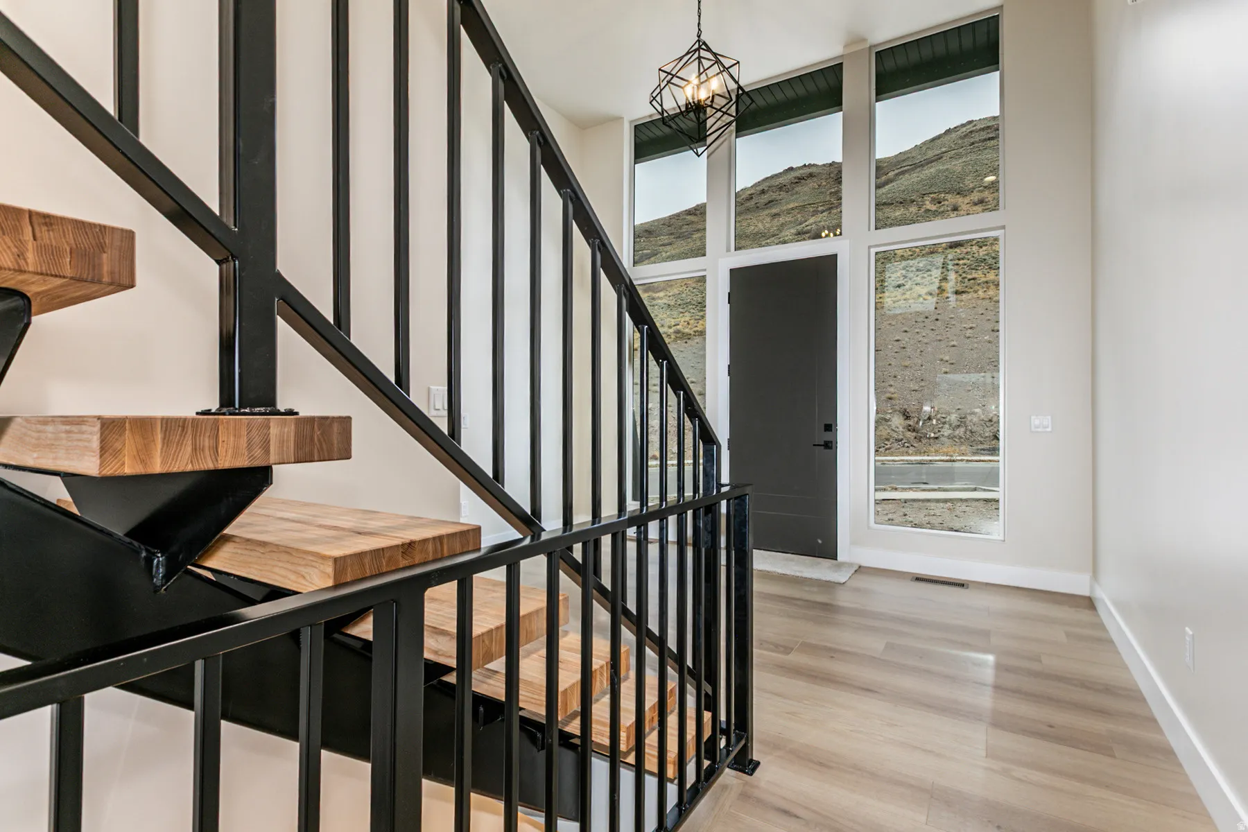 Two-story foyer featuring an open-riser staircase with wood-finish treads and black metal railings