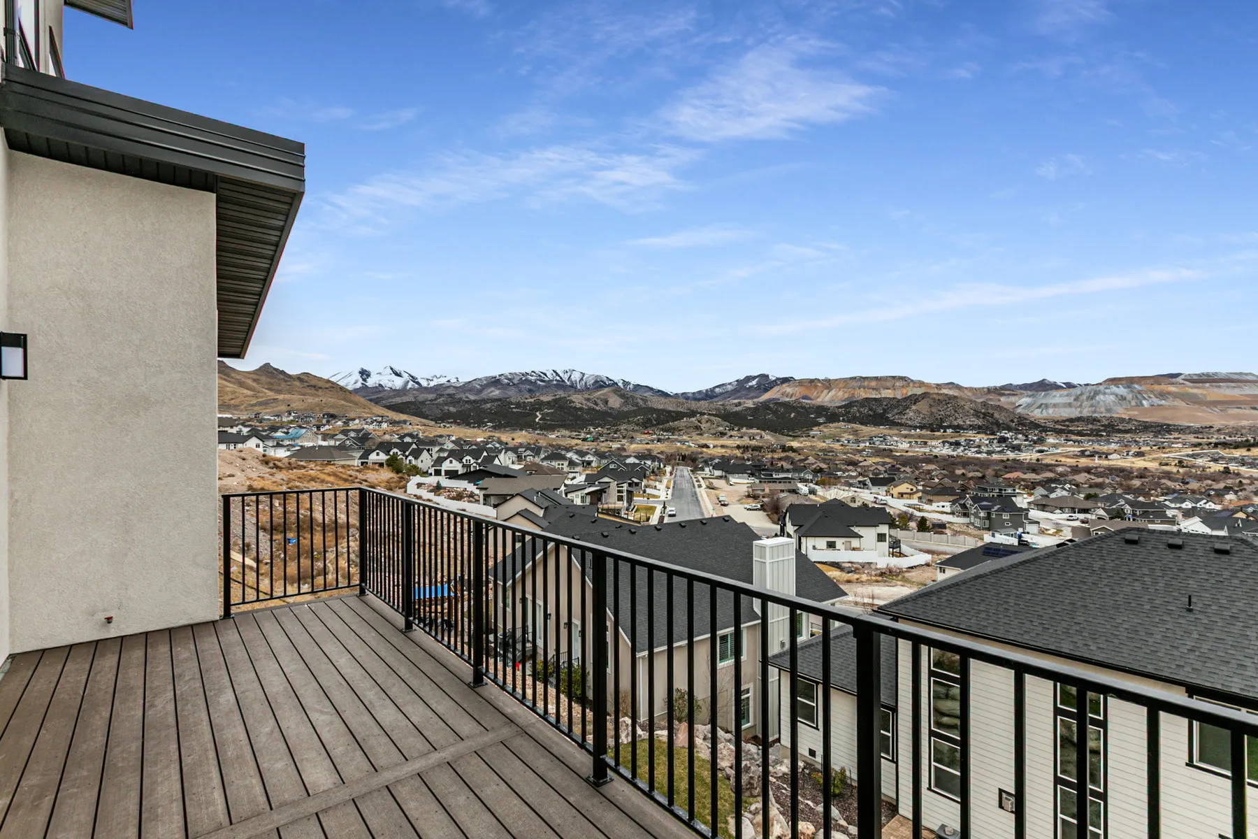 Spacious outdoor balcony with composite decking and black metal railings, offering expansive mountain and neighborhood scenery