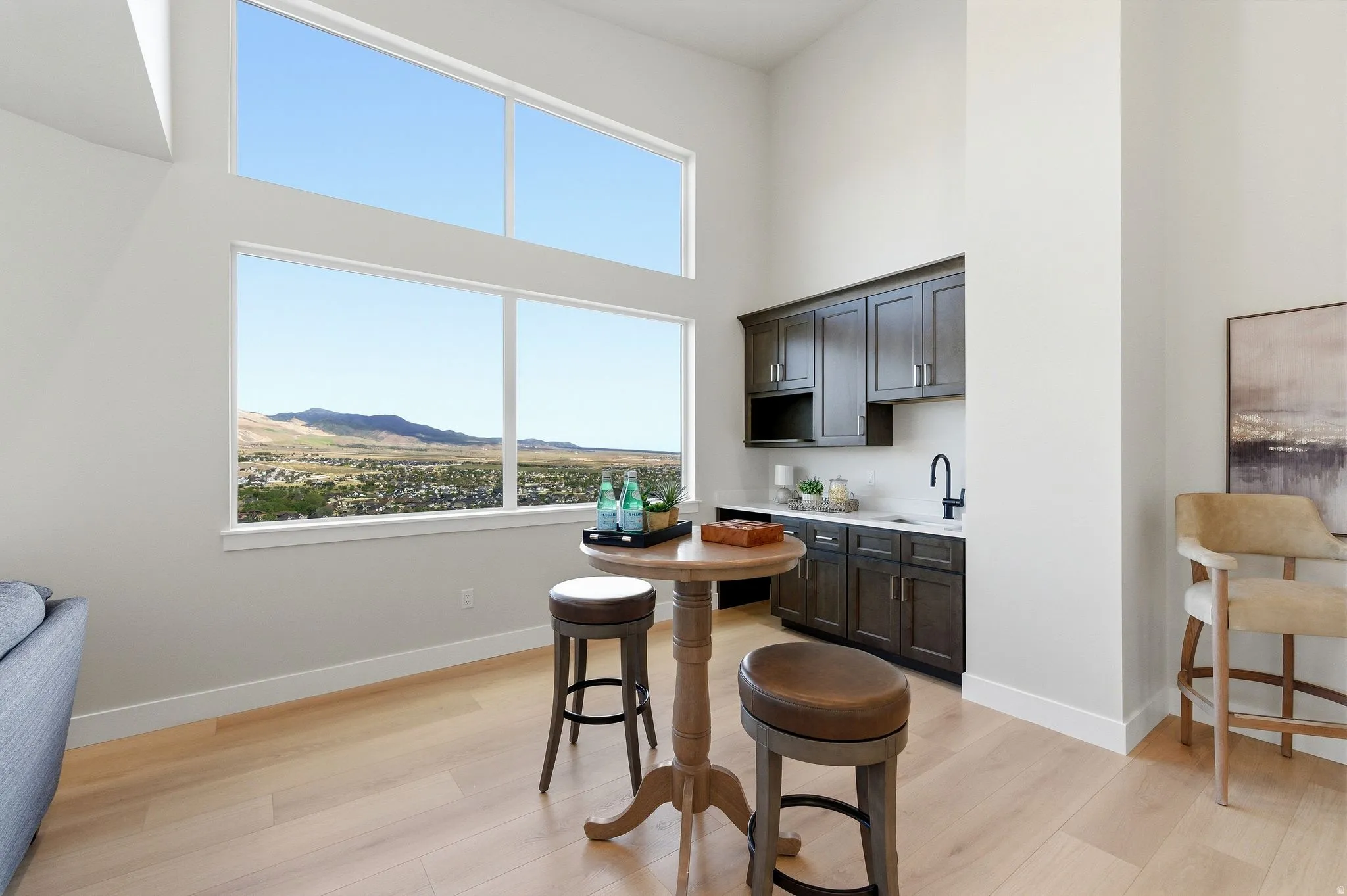 Expansive window wall with mountain scenery, dual-height ceilings, and wood-finish flooring