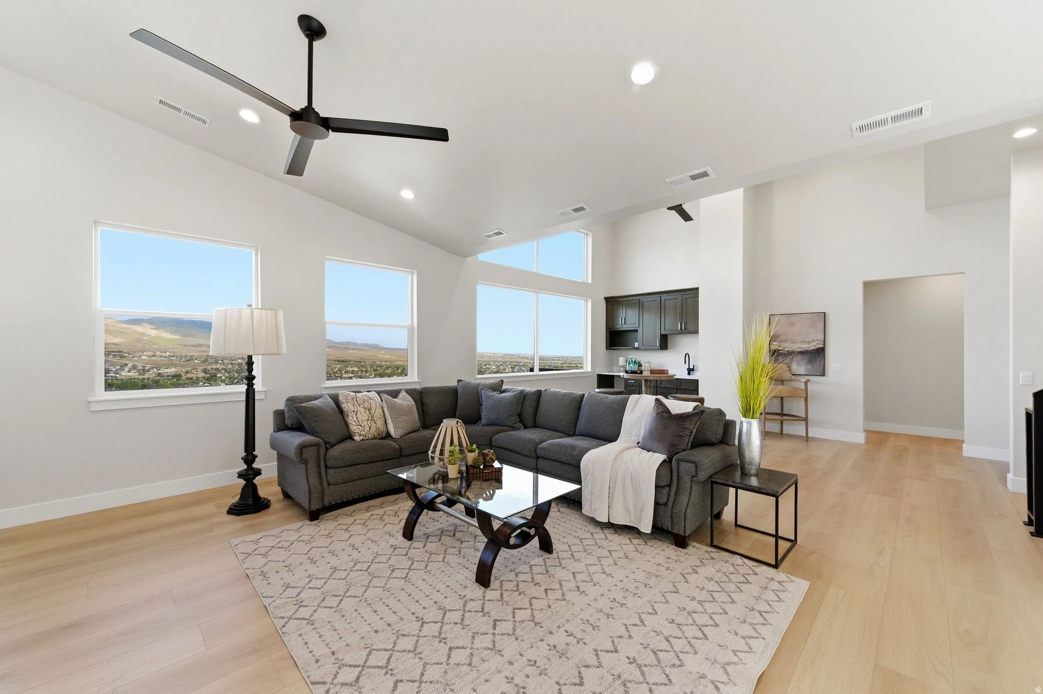 Spacious living area featuring a vaulted ceiling with a modern ceiling fan, recessed lighting, and numerous windows