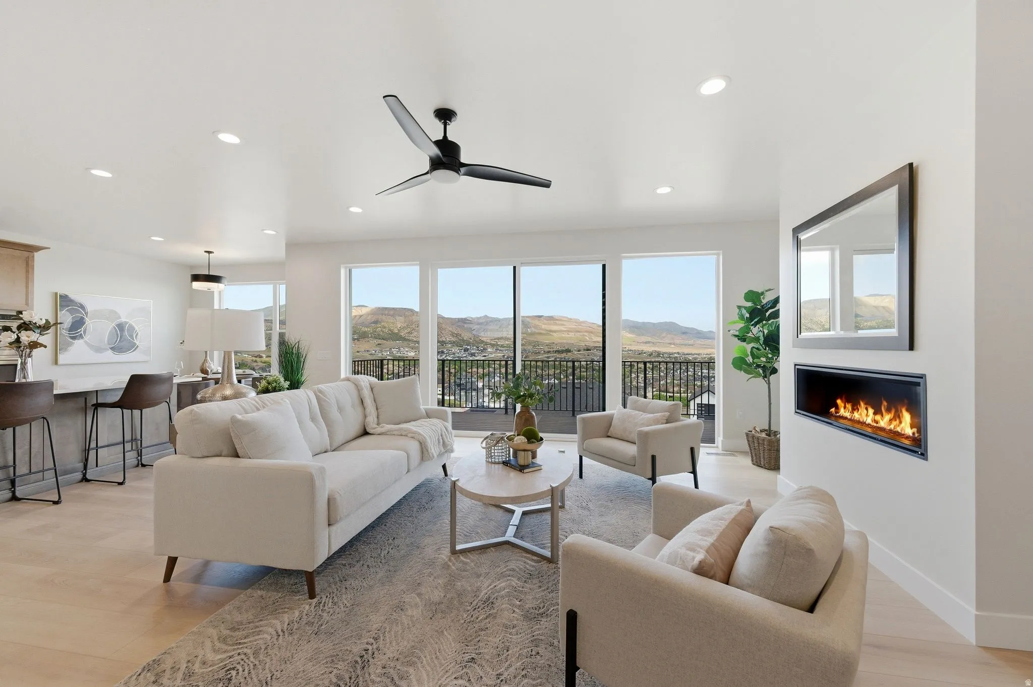 Bright living area featuring expansive windows, a sleek linear fireplace, wood-finish flooring, recessed lighting, and a contemporary ceiling fan