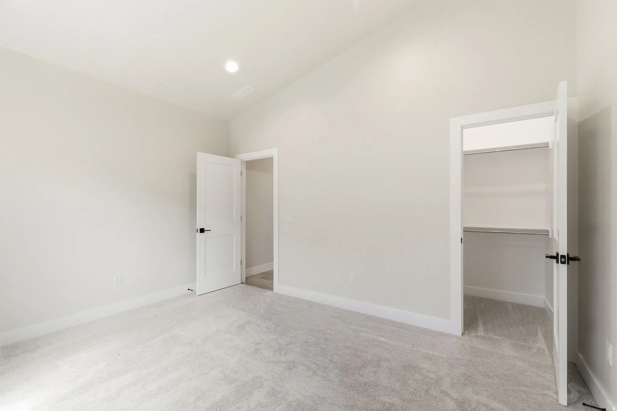 Spacious room with light gray carpet flooring, white painted walls, white trim, recessed lighting, and a closet with built-in shelving