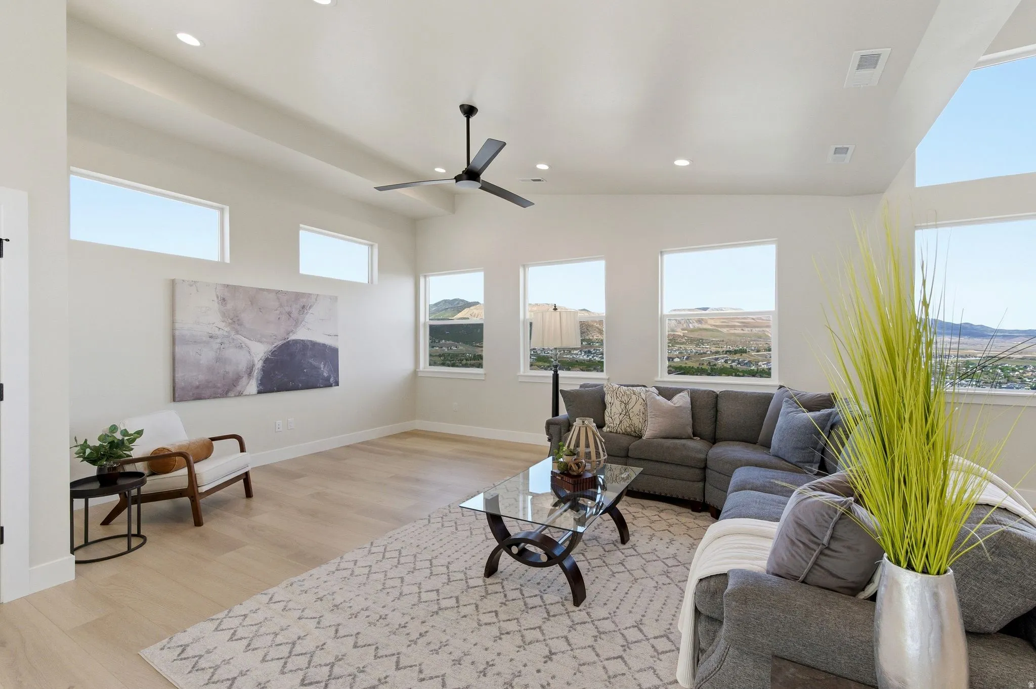 Living area featuring wood-finish flooring, recessed lighting, a ceiling fan, multiple windows, and high ceilings