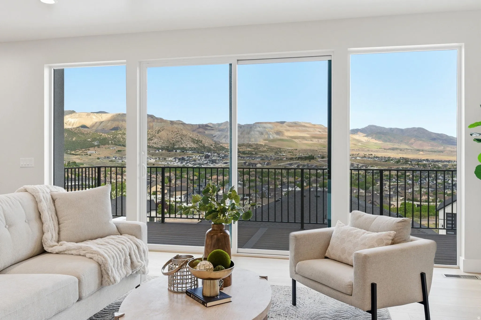 Floor-to-ceiling windows with a sliding glass door provide expansive mountain and distant community scenery